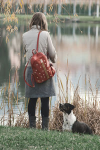 Rear view of woman standing with dog by lake