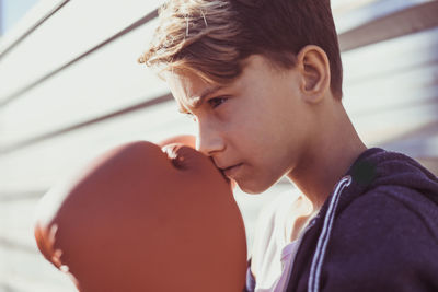 Close-up of boy wearing red boxing gloves outdoors