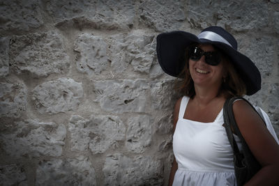 Portrait of a smiling young woman standing against wall