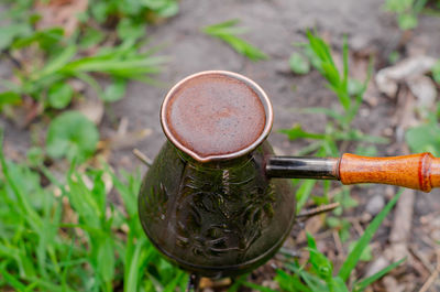 Aromatic delicious coffee in copper patterned turk with wooden handle. coffee in the woods on grass. 