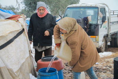 Rear view of people standing on road in winter