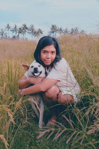 Portrait of woman with dog on field