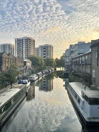 Canal amidst buildings in city against sky