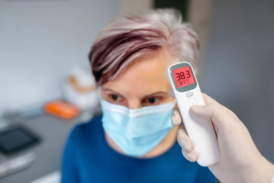 Portrait of young woman holding thermometer