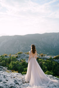 Woman with umbrella on mountain against sky