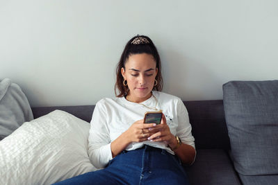 Young man using mobile phone while sitting on sofa