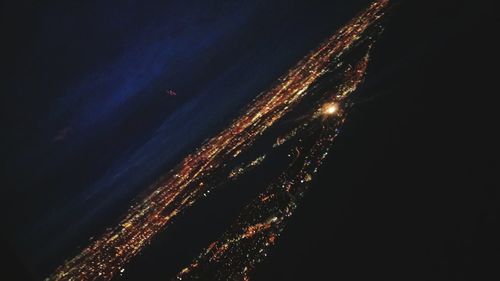 Low angle view of illuminated sea against sky at night