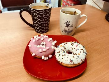 High angle view of coffee cups and donuts in plate on table