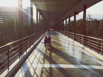 Rear view of boy with cart walking on footbridge