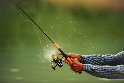 Man holding fishing rod by water