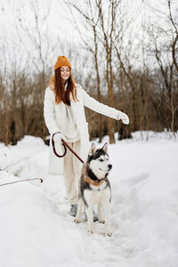 Portrait of woman with dog on snow covered field