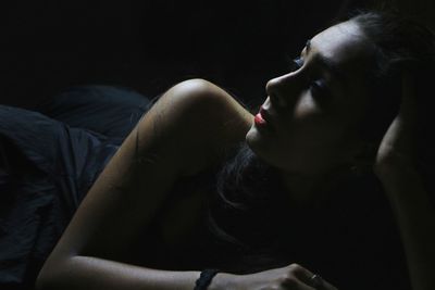 Close-up of fashion model lying against black background