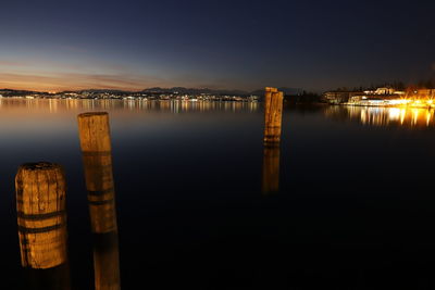 Wooden posts in lake against sky at night