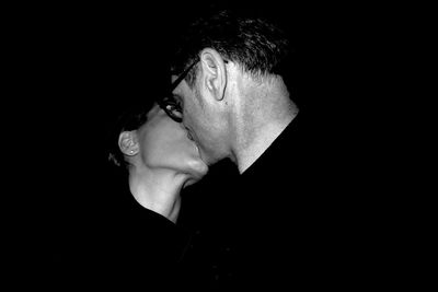 Man and woman kissing against black background