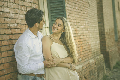 Romantic couple standing by brick wall