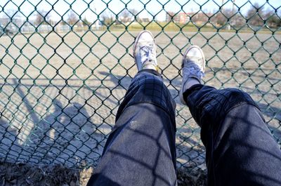 Low section of man on chainlink fence