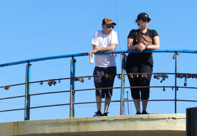 Low angle view of friends against clear blue sky