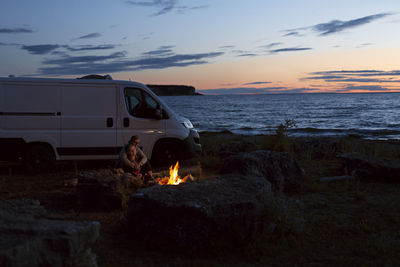 Couple relaxing at log fire by sea