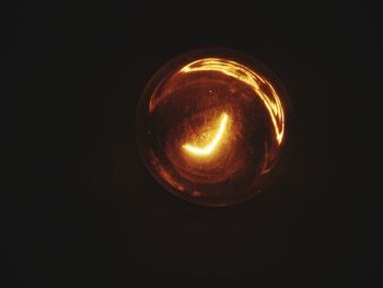 Close-up of illuminated light bulb against black background