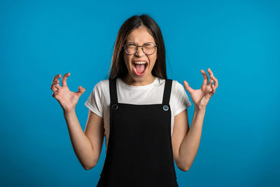 Portrait of a young woman standing against blue background