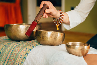 Cropped hand of therapist playing rin gong on young woman at spa