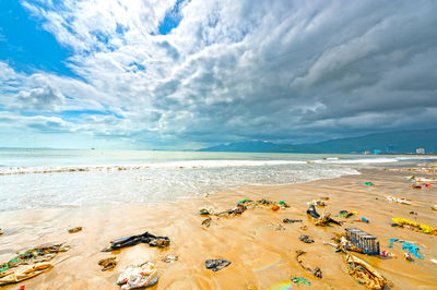 Scenic view of beach against cloudy sky