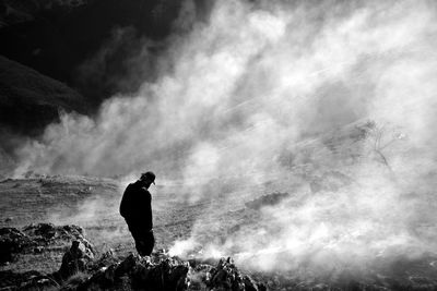 Silhouette man on rock against sky