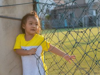 Portrait of girl standing against fence