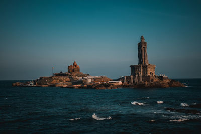 View of building by sea against blue sky