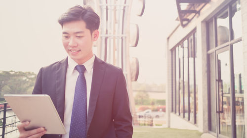 Smiling young businessman using digital tablet