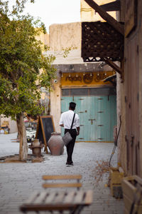 Rear view of man walking on footpath against building