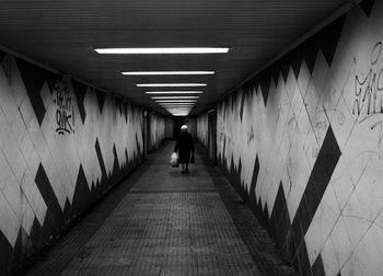 Rear view of woman walking in subway tunnel