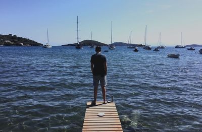 Rear view of man standing on jetty