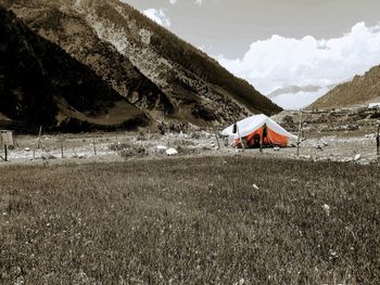 Tent on field by mountain against sky