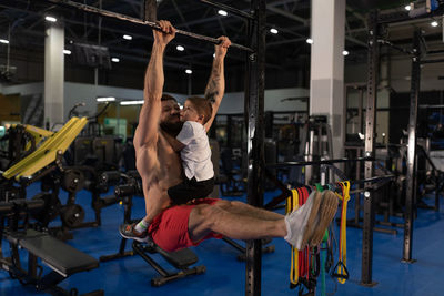 Muscular father exercising on bar with son