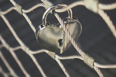 Close up of heart shaped padlock attached in chainlink railing