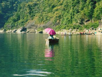 Woman fishing while sitting in boat on lake