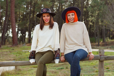 Portrait of smiling women sitting on railing at park