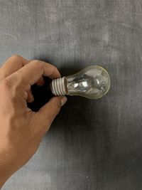 High angle view of hand holding paper against wall