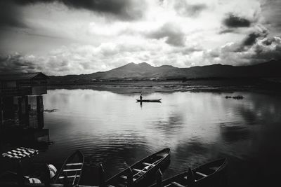 Boats in sea against cloudy sky