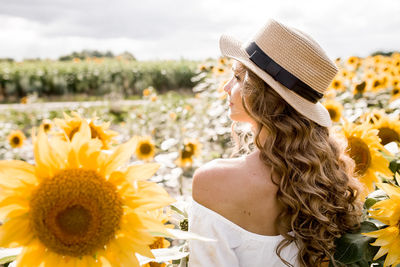 A young girl with a model appearance, in denim trousers and a white blouse in a sunflower field