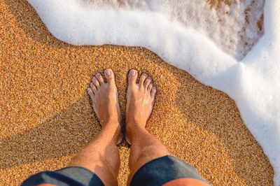 Low section of woman standing on sand at beach