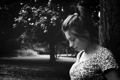 Woman standing by tree trunk