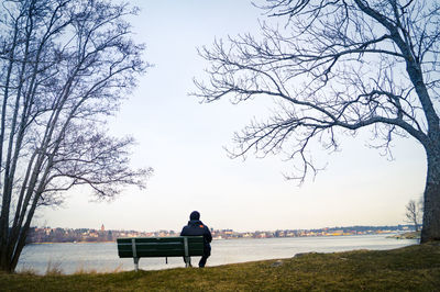 Rear view of woman relaxing on lakeshore