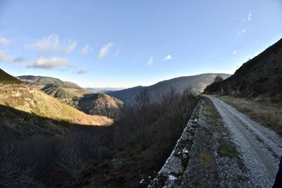 Road by mountains against sky