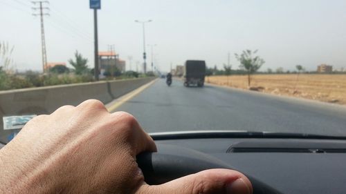 Close-up of hand holding car moving on road