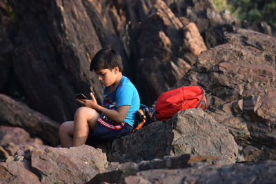 Rear view of boy sitting on rock