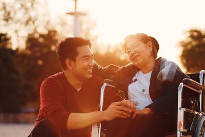 Smiling senior woman with grandson sitting on wheelchair outdoors