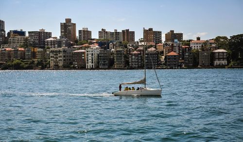 Sailboat sailing on sea against buildings in city