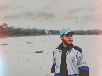 Portrait of young man standing on wet window